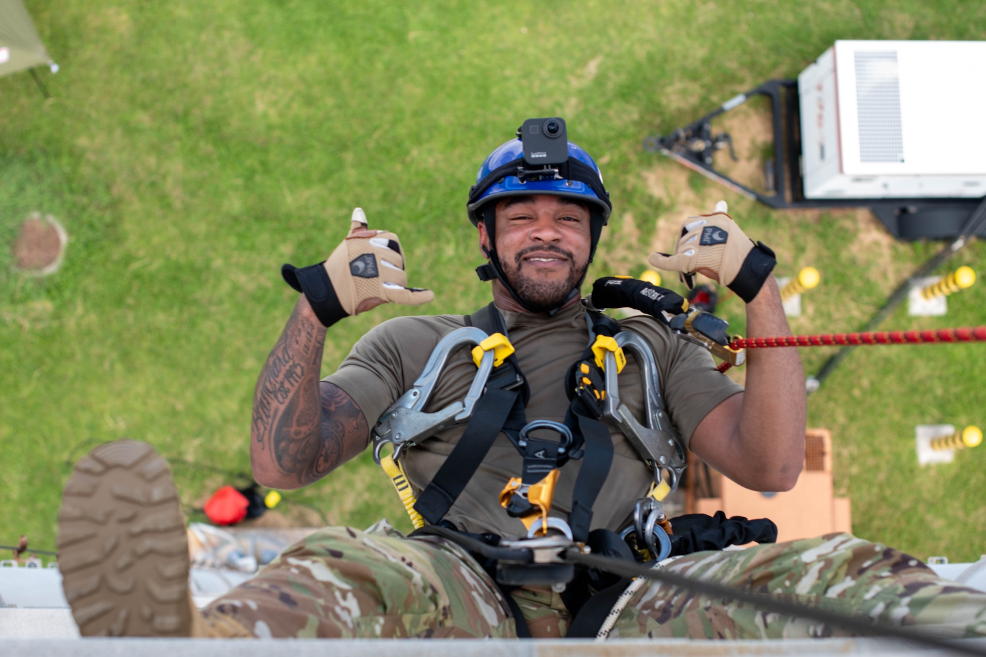 military member hangs from rope while rappelling down a tower