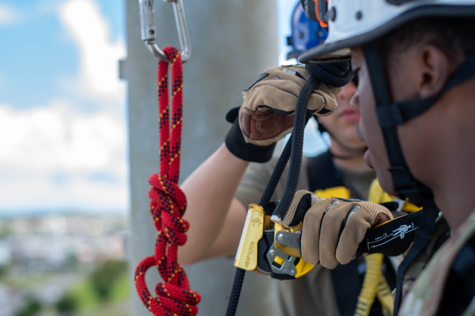 Airman helps another Airman with tightening rappelling rope and harness