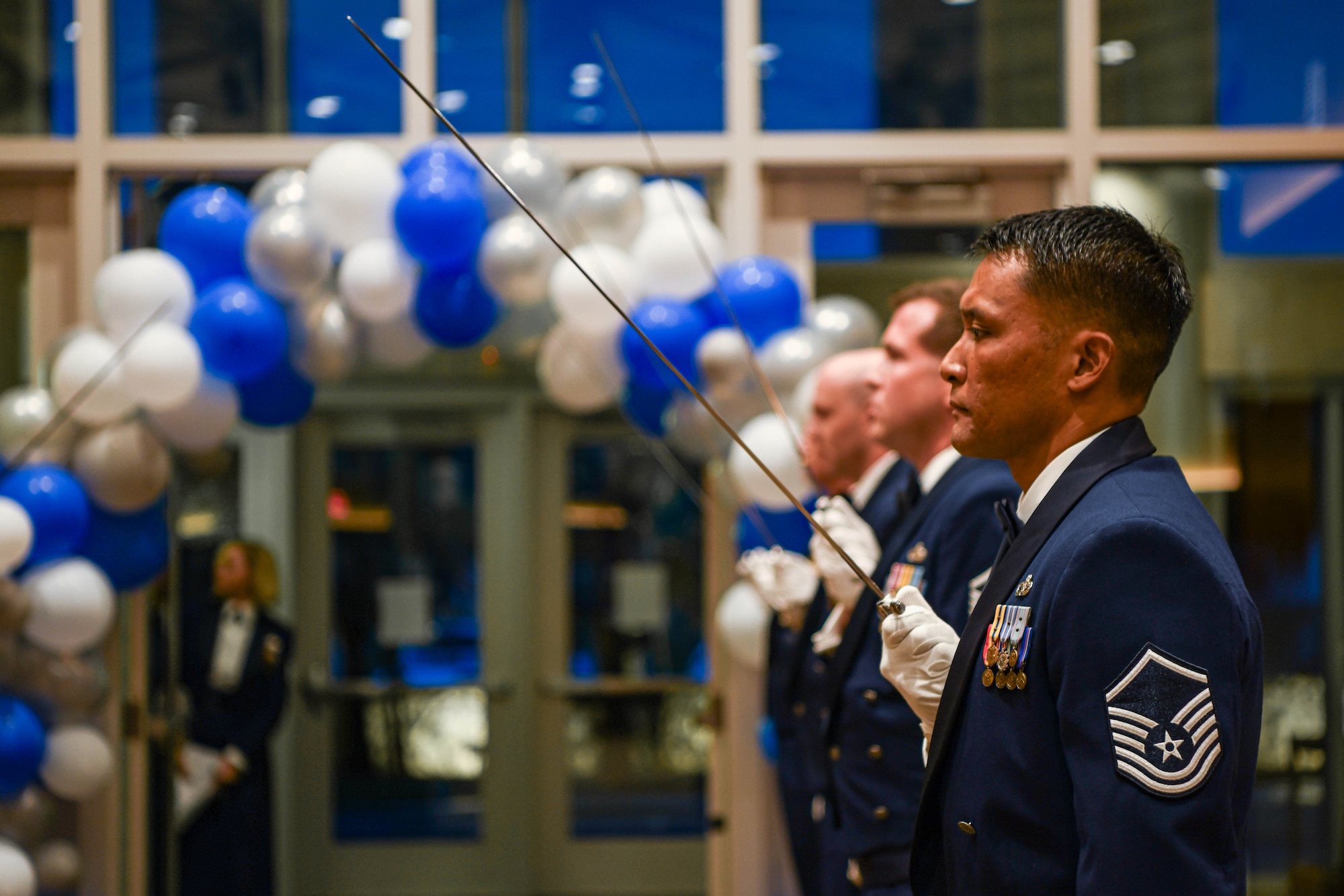 An SNCO holds up a saber during an event.