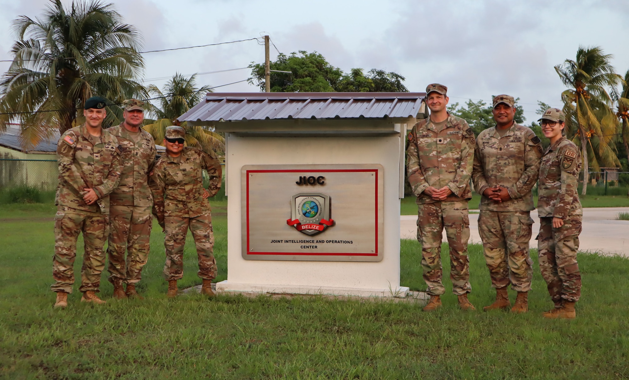 A photo of service members posing in front of a sign.