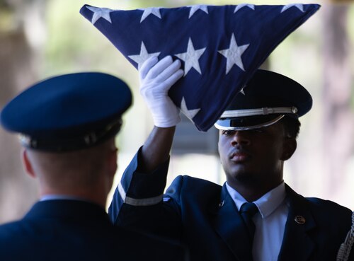 Airman 1st Class Maurice Sheppard, ceremonial guardsman, brings the American flag down past his face during the Team Eglin Honor Guard Graduation ceremony.