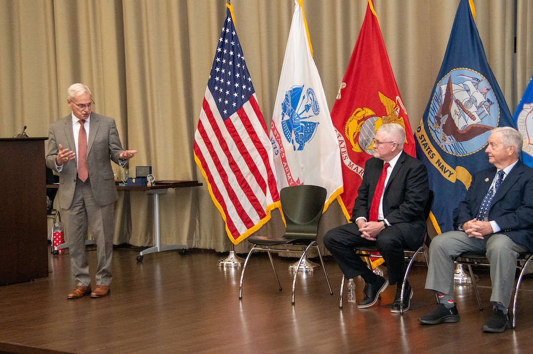 Three people on stage during a ceremony.