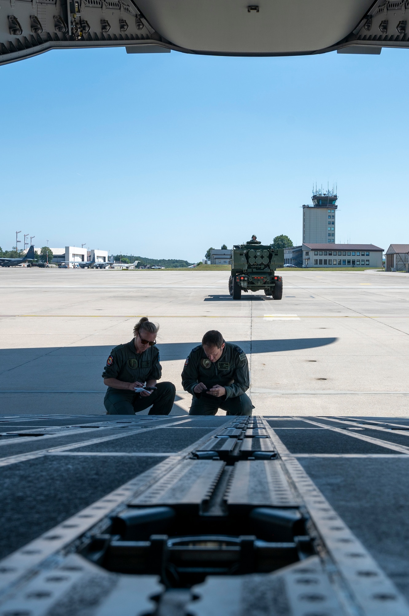 Belgian Air Component 1st Sergeant Major An Adriaenssen, 20th Squadron Transport Conversion Unit loadmaster, and Belgian Air Component Warrant Officer Roly Hartwell, 20th Squadron Transport Conversion Unit loadmaster instructor, prepare to load a U.S. Army M142 High Mobility Rocket System (HIMARS) on a Belgian A400M Atlas during a HIMARS Rapid Insertion (HIRAIN) training at Ramstein Air Base, Germany, July 29, 2024.