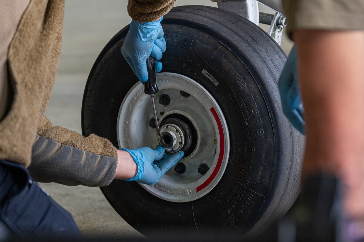 Two crew chiefs change a tire of an F-15E Strike Eagle.