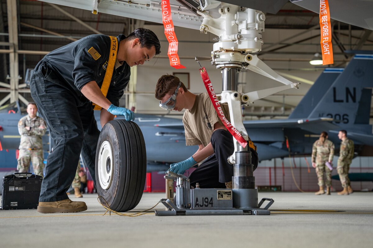 Two crew chiefs change a tire of an F-15E Strike Eagle.