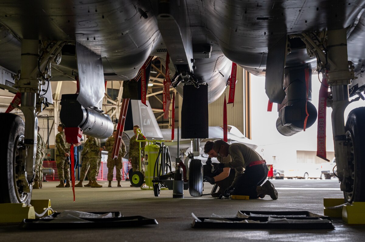 Two crew chiefs change a tire of an F-15E Strike Eagle.