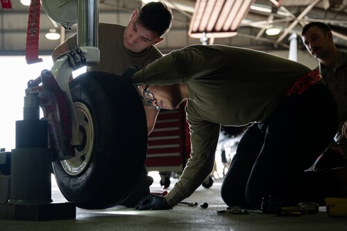 Two crew chiefs change a tire of an F-15E Strike Eagle.