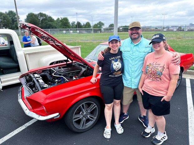 JOINT BASE ANACOSTIA-BOLLING, Washington, D.C. (July 30, 2024) - Dr. Greg Bouton (center) and his two daughters pose for a picture with their 1968 Ford Mustang during Strategic Systems Programs' (SSP) annual command picnic, Tuesday. Bouton and his daughters have teamed together for months to build and restore the Mustang. This year's event for SSP staff and their families included food, games, a dunk tank, and the car show which featured vehicles--old and new--owned by members of the SSP workforce. The picnic was organized by SSP’s Activity and Recreations Committee (SPARC), an all-volunteer team made up of military and civilians who fundraise and plan MWR events throughout the year. SSP is the Navy command that provides cradle-to-grave lifecycle support for the sea-based leg of the nation’s nuclear triad. (U.S. Navy Photo by Lt. Jennifer Bowman/Released)