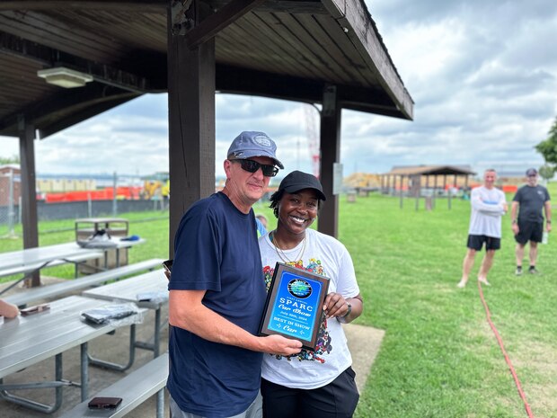 JOINT BASE ANACOSTIA-BOLLING, Washington, D.C. (July 30, 2024) - Strategic Systems Programs (SSP) Director Vice Adm. Johnny Wolfe Jr. (left) awards Cotina Harper (right) 'Best in Show' for her BMW i7 after votes were tallied during the command's annual picnic Tuesday. This year's event for SSP staff and their families included food, games, a dunk tank, and the car show which featured vehicles--old and new--owned by members of the SSP workforce. The picnic was organized by SSP’s Activity and Recreations Committee (SPARC), an all-volunteer team made up of military and civilians who fundraise and plan MWR events throughout the year. SSP is the Navy command that provides cradle-to-grave lifecycle support for the sea-based leg of the nation’s nuclear triad. (U.S. Navy Photo by Lt. Jennifer Bowman/Released)