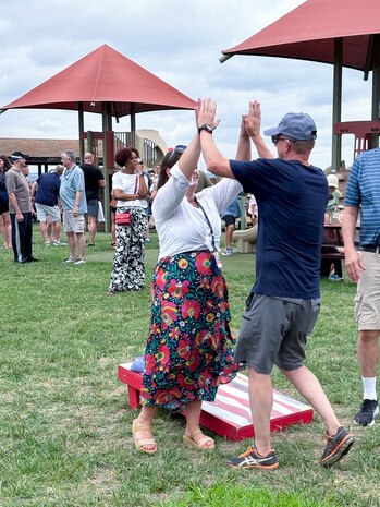 JOINT BASE ANACOSTIA-BOLLING, Washington, D.C. (July 30, 2024) - Strategic Systems Programs (SSP) Director Vice Adm. Johnny Wolfe Jr. (right) gives a high-five to Program Analyst Lisa Garcia (left) during a friendly competition of cornhole during the command's annual  picnic, Tuesday. This year's event for SSP staff and their families included food, games, a dunk tank, and the car show which featured vehicles--old and new--owned by members of the SSP workforce. The picnic was organized by SSP’s Activity and Recreations Committee (SPARC), an all-volunteer team made up of military and civilians who fundraise and plan MWR events throughout the year. SSP is the Navy command that provides cradle-to-grave lifecycle support for the sea-based leg of the nation’s nuclear triad. (U.S. Navy Photo by Shelby Thompson/Released)