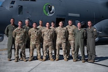 Uniformed aircrew stand in front of a large military aircraft