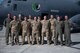 Uniformed aircrew stand in front of a large military aircraft