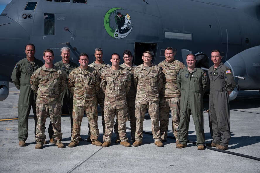 Uniformed aircrew stand in front of a large military aircraft