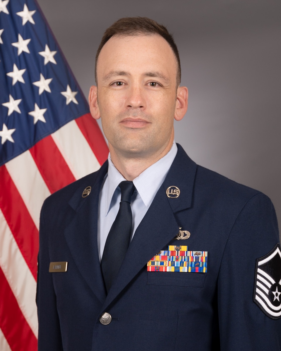 Official photo of MSgt Craig Larimer with American flag over right shoulder