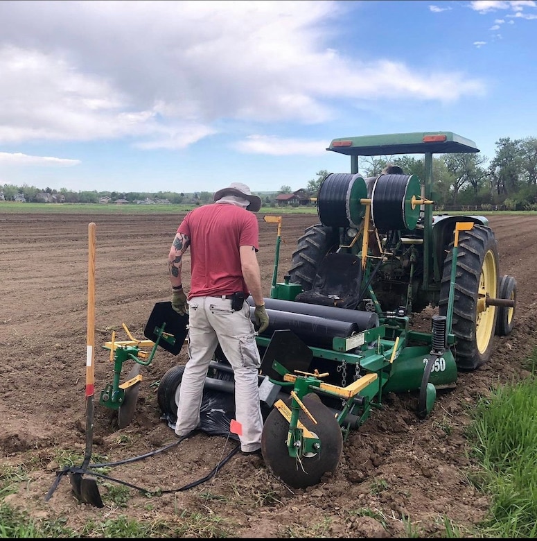 Trey Burchfield installing irrigation and plastic mulch as an Organic Farmer