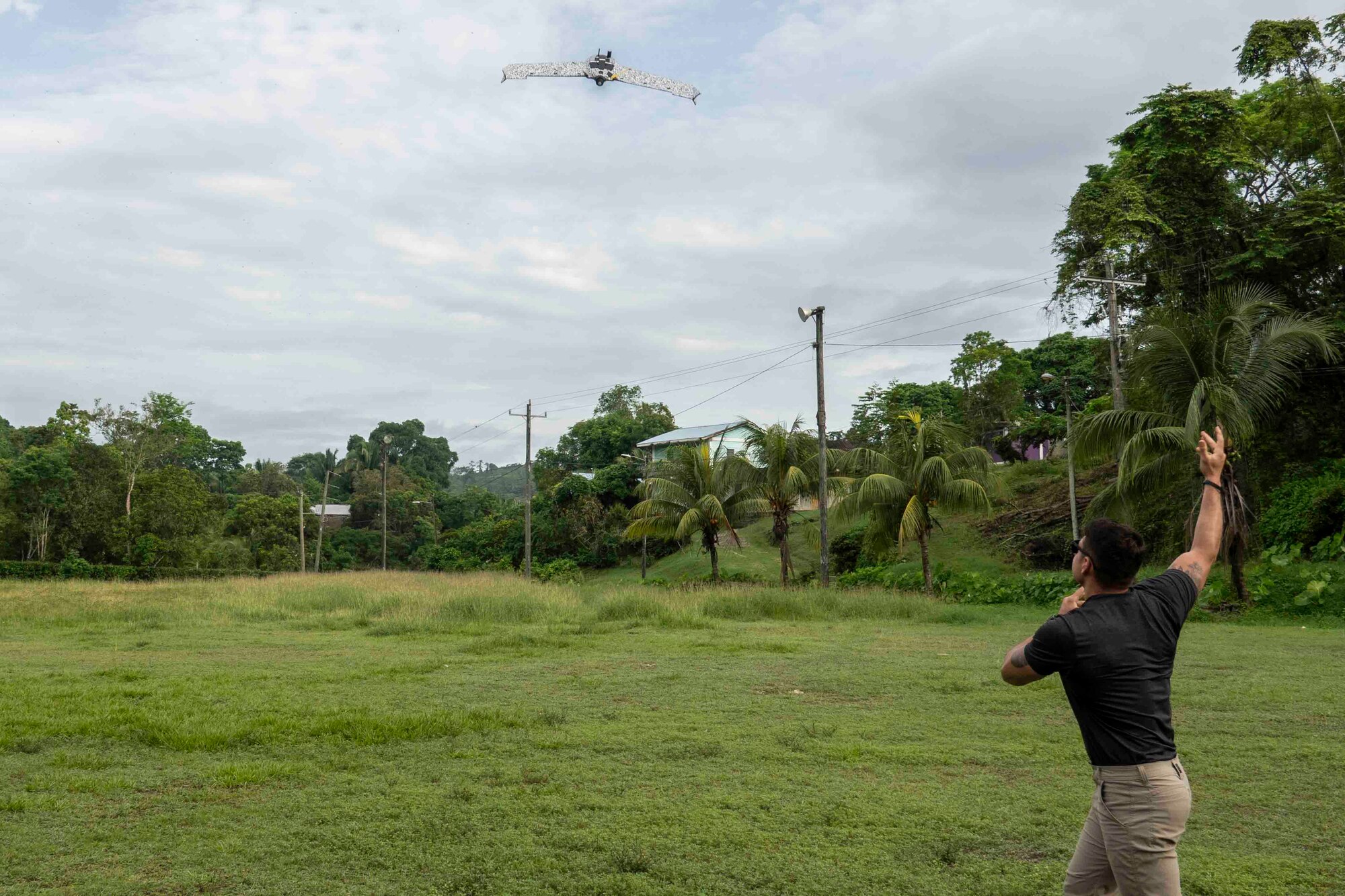 A photo of a person throwing a drone into the air in a field.
