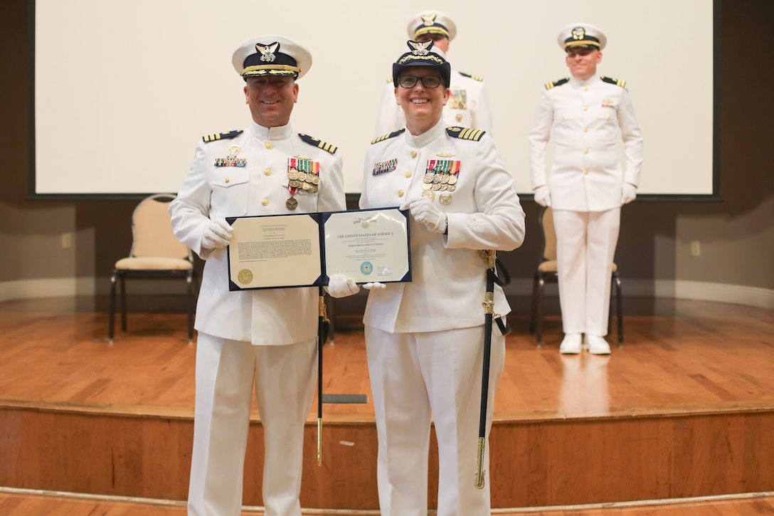 Cmdr. Brian Chapman, outgoing commanding officer of Coast Guard Cutter Reliance (WMEC 615), and Capt. Kristen Serumgard, presiding official at the cutter's change-of-command ceremony, pose for a photo after Chapman was awarded the Meritorious Service Medal, July 25, at Naval Air Station Pensacola, Florida. The change-of-command ceremony is a time-honored tradition that serves to formally demonstrate the continuity of authority within a command in front of the crew and esteemed guests. (U.S Coast Guard photo by Petty Officer 2nd Class Tyler Goldberg)