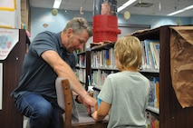 Rob Birke, Strategic Weapons Facility, Atlantic (SWFLANT) Security Operations Supervisor, helps a child prepare his straw missile for launch at the Camden County Public Library in Kingsland, Georgia, June 28, 2024. A team of volunteers from SWFLANT, Lockheed Martin and General Dynamics hosted the event during the Science, Technology, Engineering, and Mathematics (STEM) day of the library’s summer learning series. (U.S. Navy photo by Ashley Berumen)