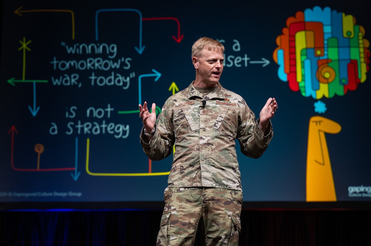 Man in USAF uniform talks on a stage.