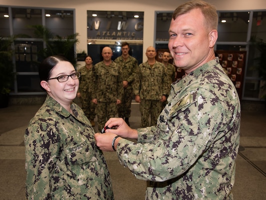 Navy Intelligence Specialist 2nd Class Petty Officer Sarah Redsicker, a native of Chili, New York and assigned as a Cyber Threat Intelligence (CTI) analyst for Naval Information Warfare Center (NIWC) Atlantic’s Cybersecurity Service Provider (CSSP) team, is frocked to Petty Officer 1st Class by Lt. Cmdr. Daniel Kapral, NIWC Atlantic's Navy and Combatant Command portfolio manager, during a ceremony Dec. 12 in the atrium of NIWC Atlantic’s headquarters building in Charleston, South Carolina.