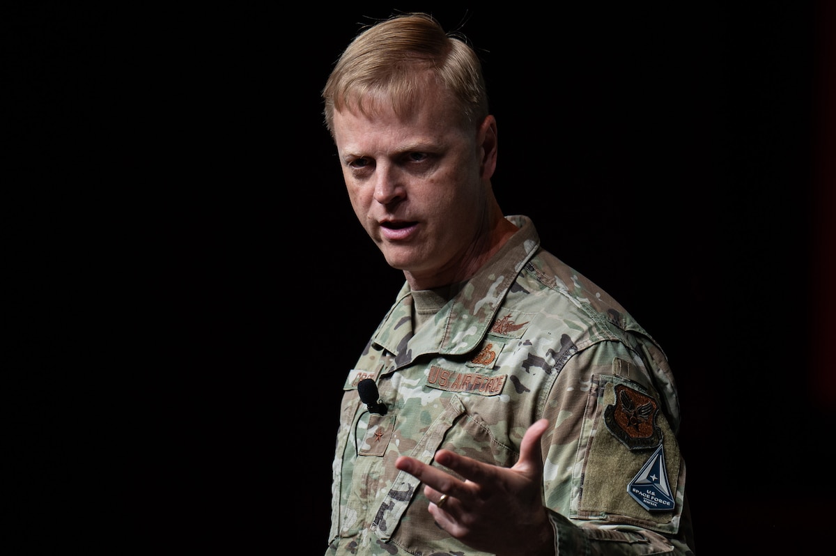 Man in USAF uniform talks on a stage.