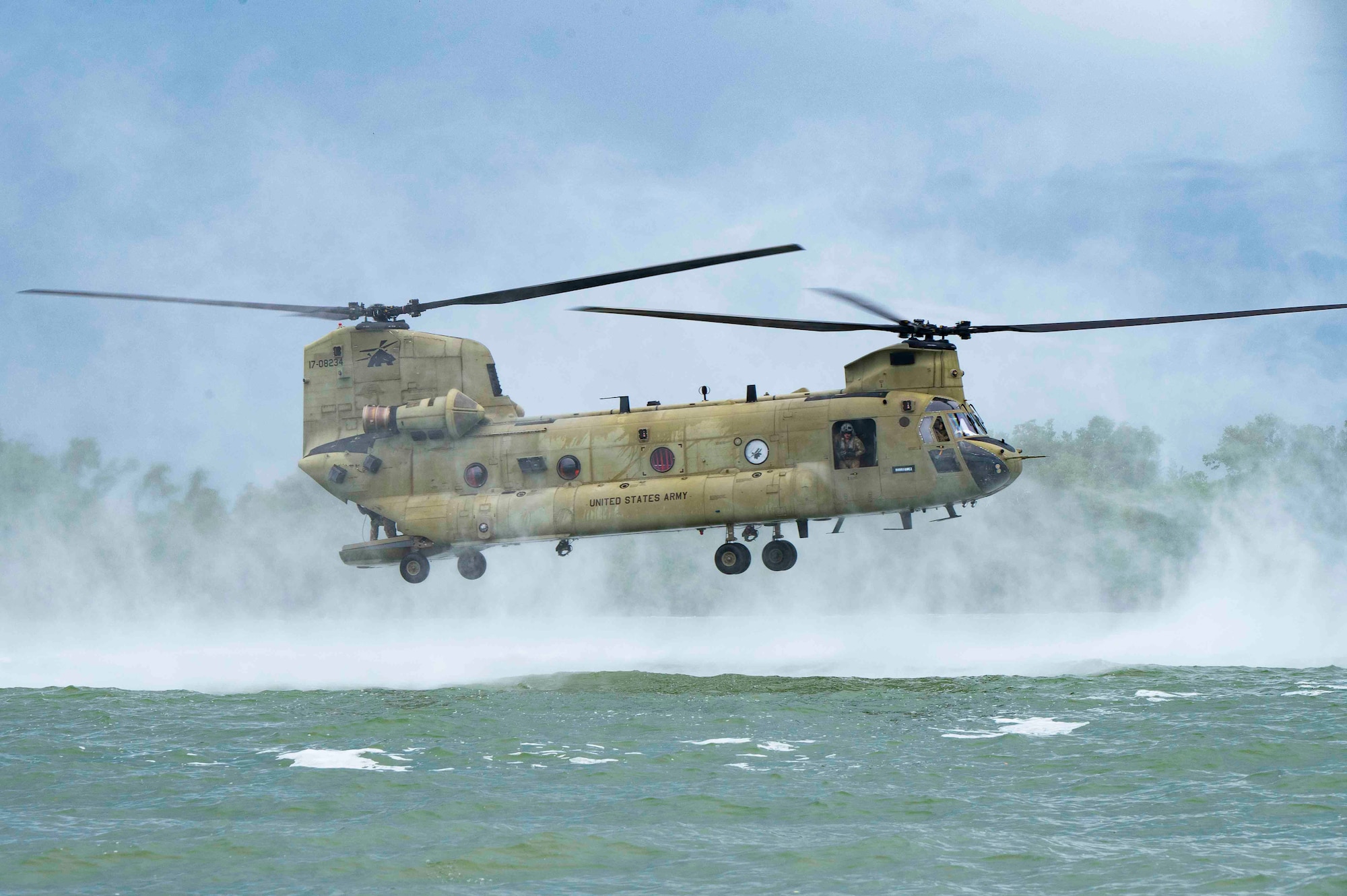 A photo of a helicopter hovering above water.