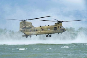 A photo of a helicopter hovering above water.