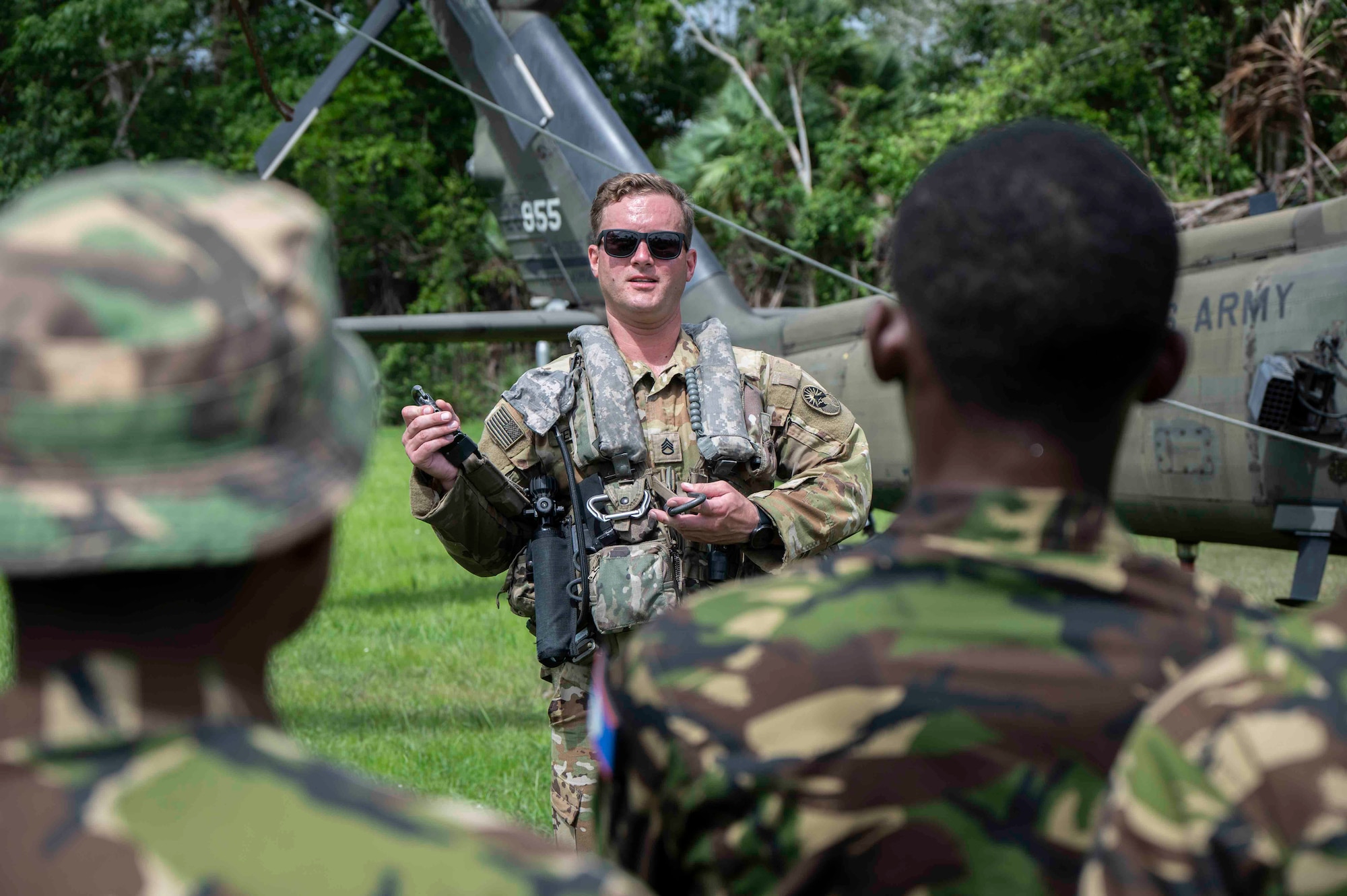 A U.S. solider showcasing flight gear to an audience of Belize service members.