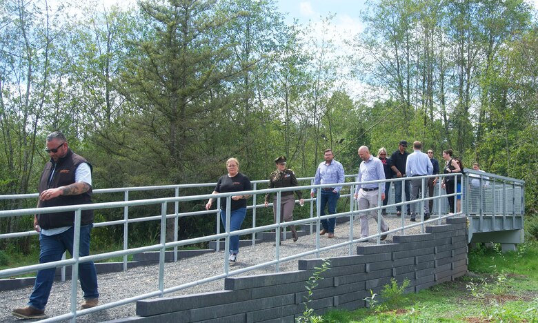 A group of people walking across a boardwalk in a community park.