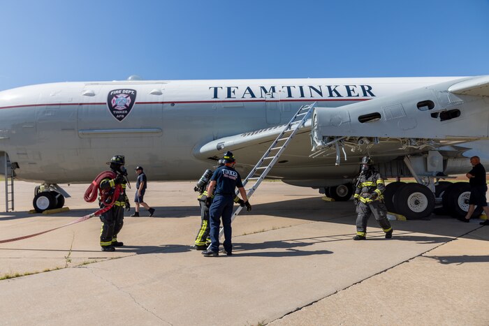 Firemen with hose and firemen with ladder on aircraft.