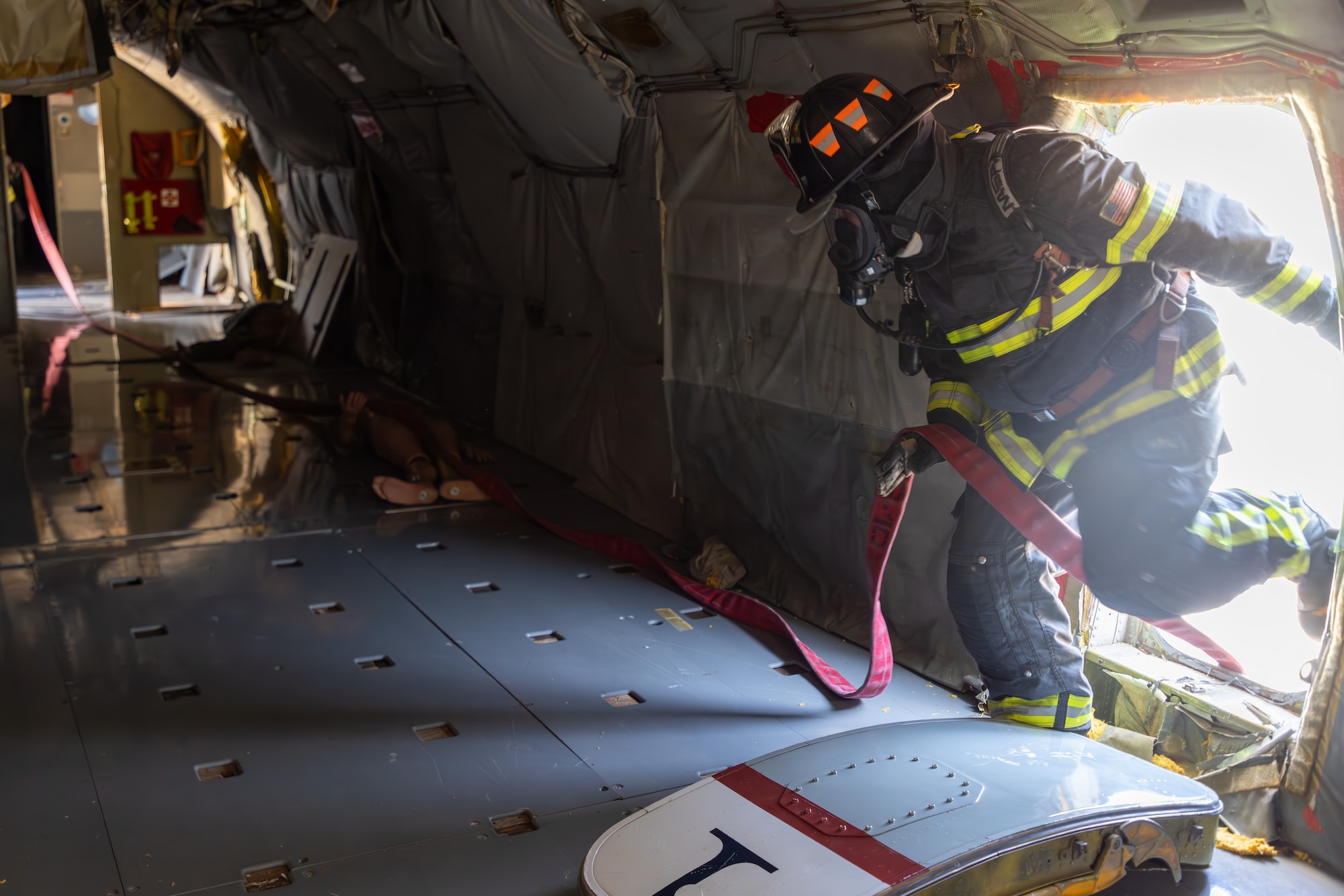 Firemen running hose into aircraft
