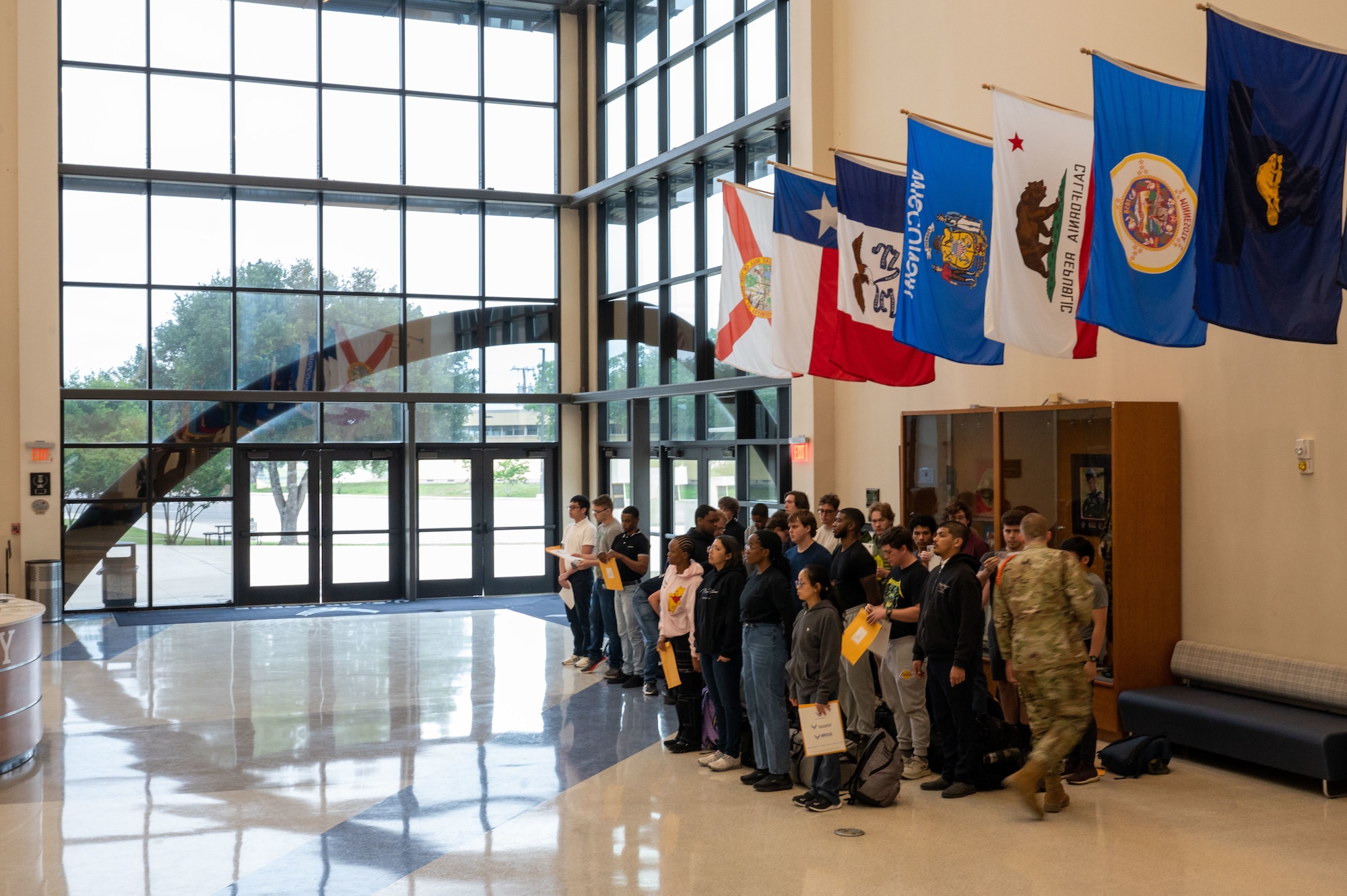 After stepping off their bus, incoming trainees line up by the Pfingston Reception Center entrance and receive their first briefing on April 23, 2024. Every Tuesday, new recruits are bussed in from the San Antonio International Airport to Joint Base San Antonio-Lackland, Texas, to begin seven-and-a-half weeks of Basic Military Training. The PRC represents the start of their transformation from civilians into Airmen. (U.S. Air Force by Ava Leone)