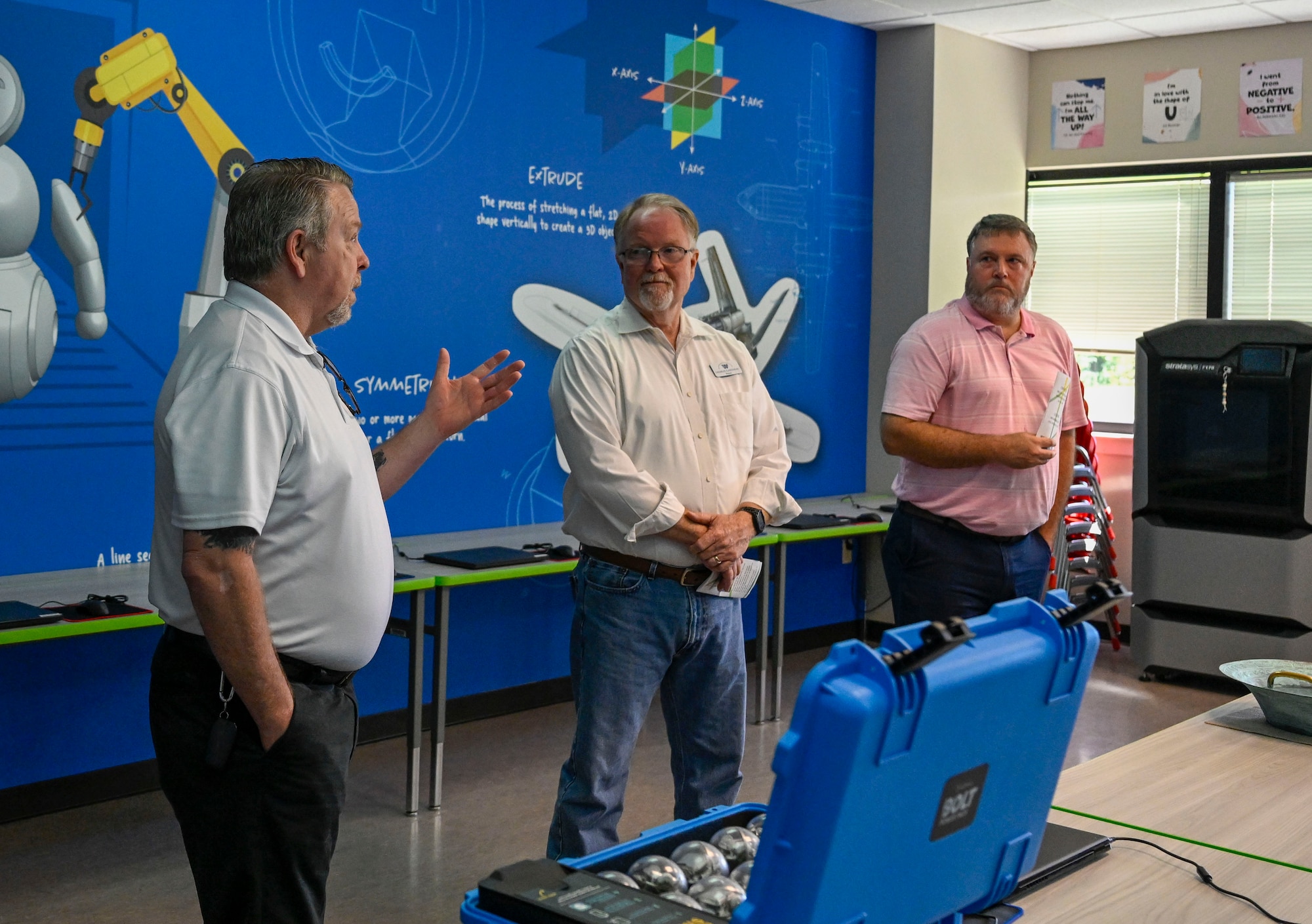 Three men stand and talk to a group of people.