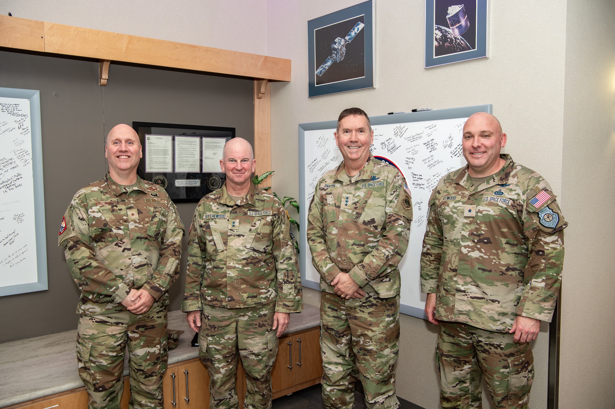 Four men in military uniforms pose for group photo