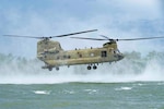 A photo of a helicopter hovering above water.