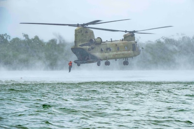 A photo of a person jumping out of a helicopter into water.