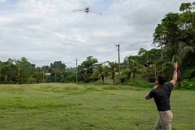 A photo of a person throwing a drone into the air in a field.