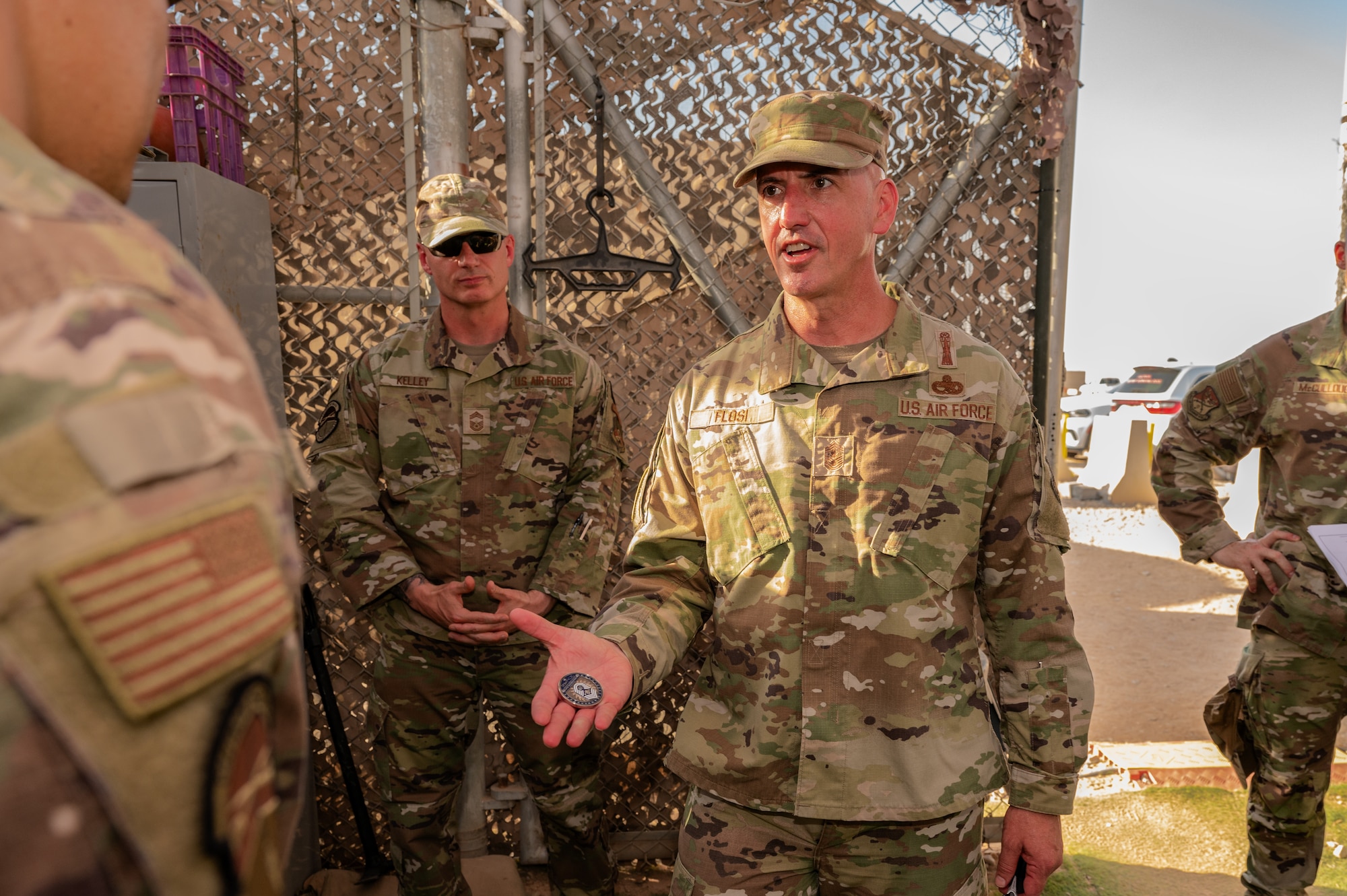 Chief Master Sgt. of the Air Force David Flosi coins a military working dog handler assigned to the 378th Expeditionary Security Forces Squadron at an undisclosed location within the U.S. Central Command area of responsibility, July 23, 2024. During his historic first visit to CENTCOM, Flosi thanked the Airmen of the 378th AEW for their sacrifices and dedication to the mission.  (U.S. Air Force photo)