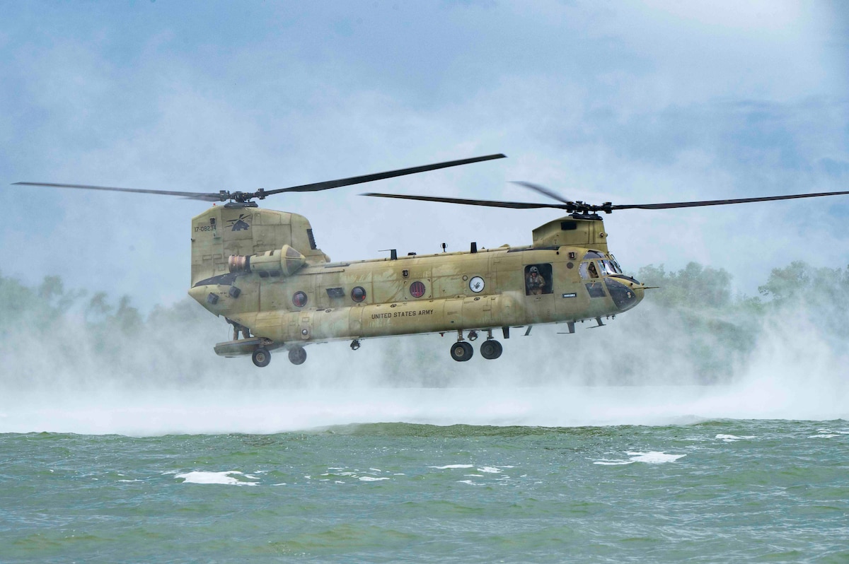 A photo of a helicopter hovering above water.