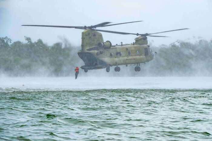 A photo of a person jumping out of a helicopter into water.