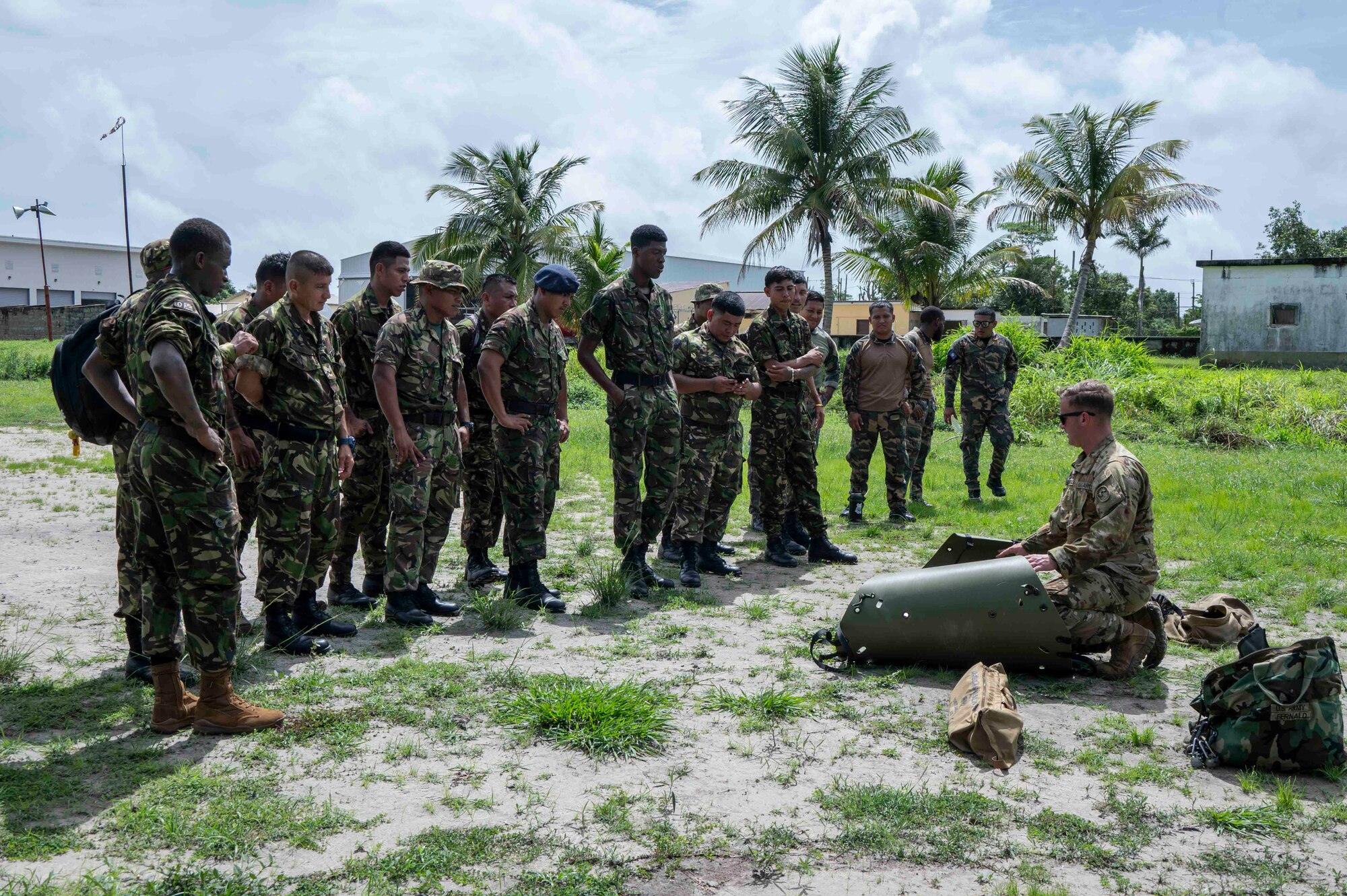 A photo of a group of Belize service members watching a U.S. soldier show recuse hoist equipment.