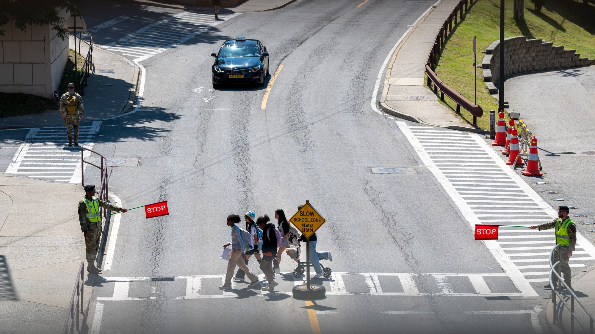 U.S. Air Force Defenders assigned to the 51st Security Forces Squadron direct traffic after a student school release at Osan Air Base, Republic of Korea, May 31, 2024. School zones are protected by 51st SFS crossing guards, who instruct drivers to keep traffic flowing smoothly and safely for Osan Airmen and their families. These crossing guards ensure that throughout the week students and family members can safely travel to and from school. (U.S. Air Force photo by Senior Airman Sabrina Fuller-Judd)
