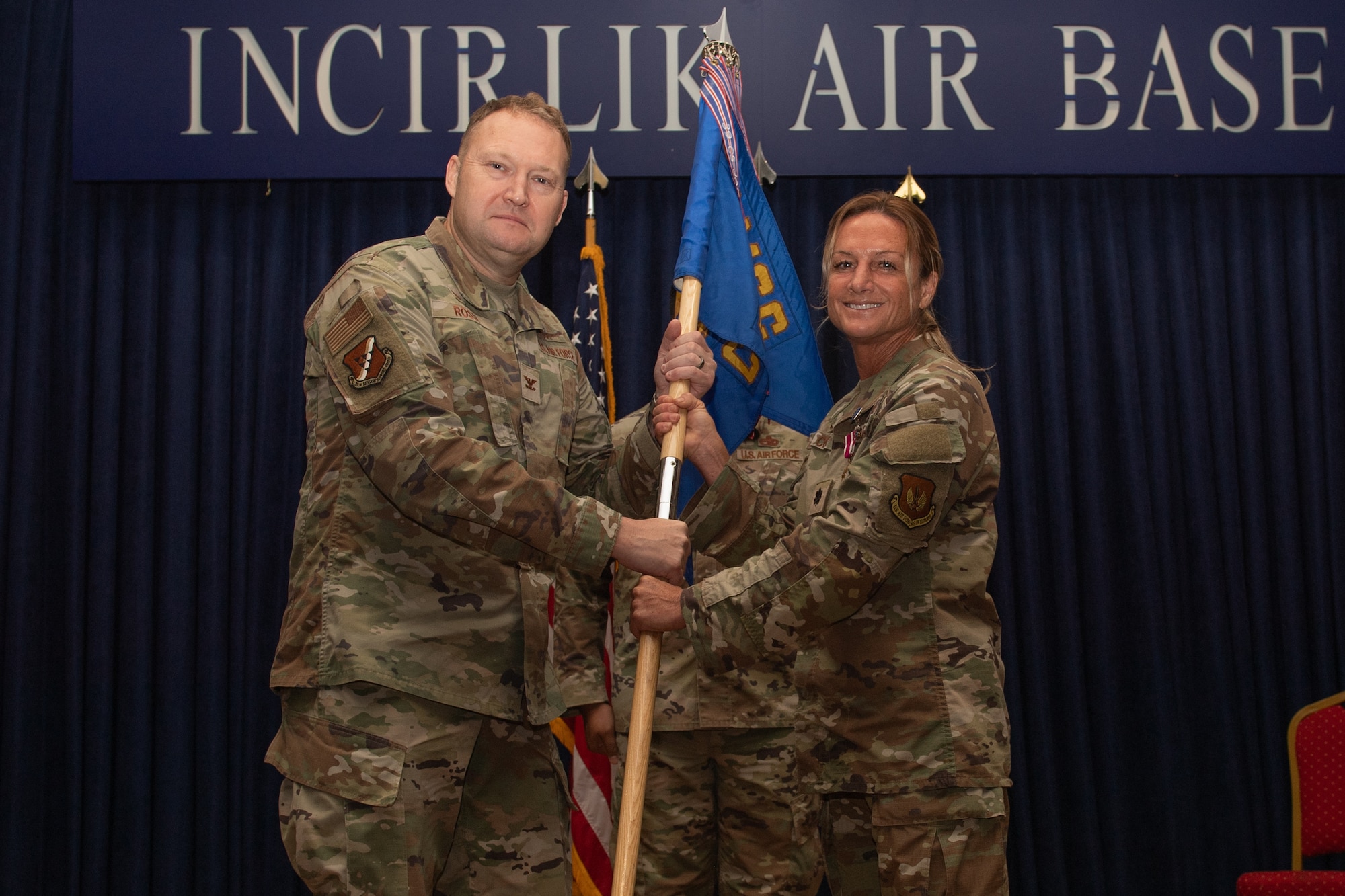 U.S. Air Force Lt. Col. Angie Cox, 39th Communications Squadron commander, relinquishes the unit guidon to Col. Jason Rossi, 39th Mission Support Group commander, during a change of command ceremony at Incirlik Air Base, Türkiye.