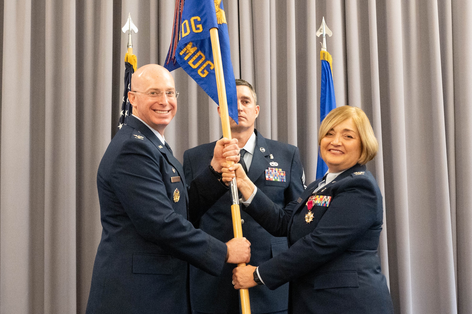 U.S. Air Force Col. Peggy Dickson, right, outgoing 436th Medical Group commander, passes the guidon to Col. Chris McDonald, 436th Airlift Wing commander, during a change of command ceremony at Dover Air Force Base, Delaware, May 30, 2024. The ceremony saw Dickson relinquish command to Col. Jamison Elder. (U.S. Air Force photo by Mauricio Campino)