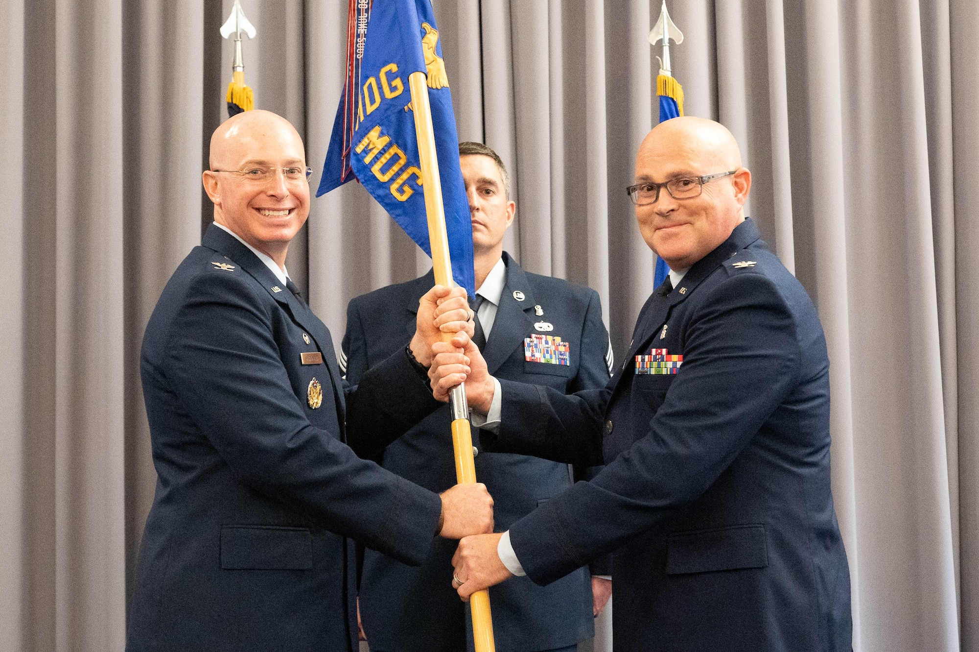 U.S. Air Force Col. Chris McDonald, left, 436th Airlift Wing commander, passes the guidon to Col. Jamison Elder, right, incoming 436th Medical Group commander, during a change of command ceremony at Dover Air Force Base, Delaware, May 30, 2024. Elder was previously the commander of the 96th Surgical Operations Squadron. (U.S. Air Force photo by Mauricio Campino)