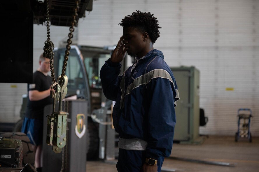 U.S. Air Force Airman James Davis, 5th Logistics Readiness Squadron inbound cargo technician, salutes ceremonial MB-1 cargo chains during the 2024 Port Dawg Memorial Run at Minot Air Force Base, North Dakota, May 30, 2024. The event honored fallen members of the air transportation specialists community who had passed away within the calendar year. (U.S. Air Force photo by Airman 1st Class Luis Gomez)