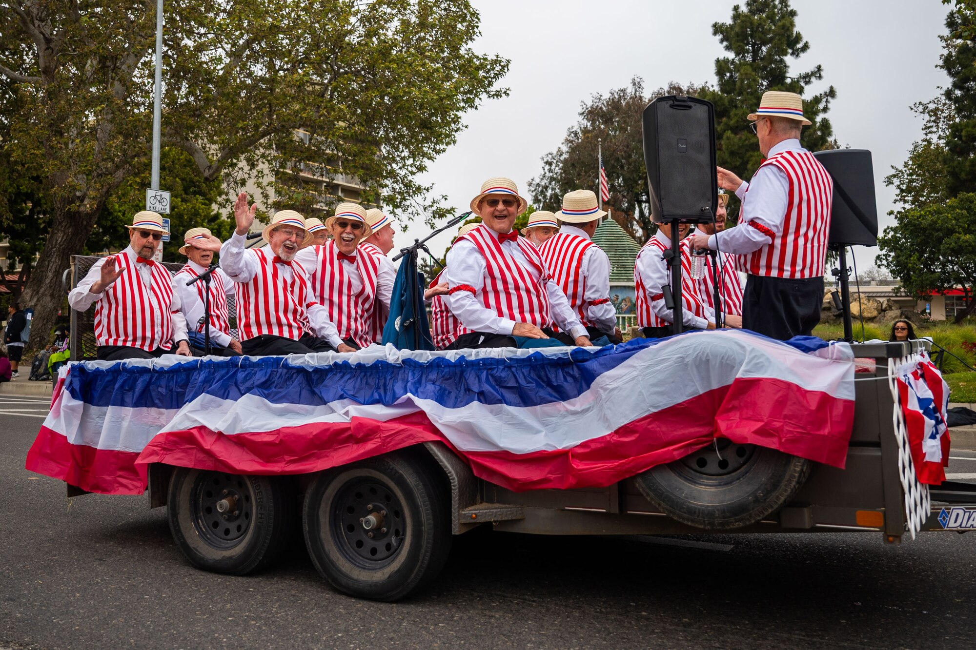 A large group of men in striped shirt sing on a parade float.