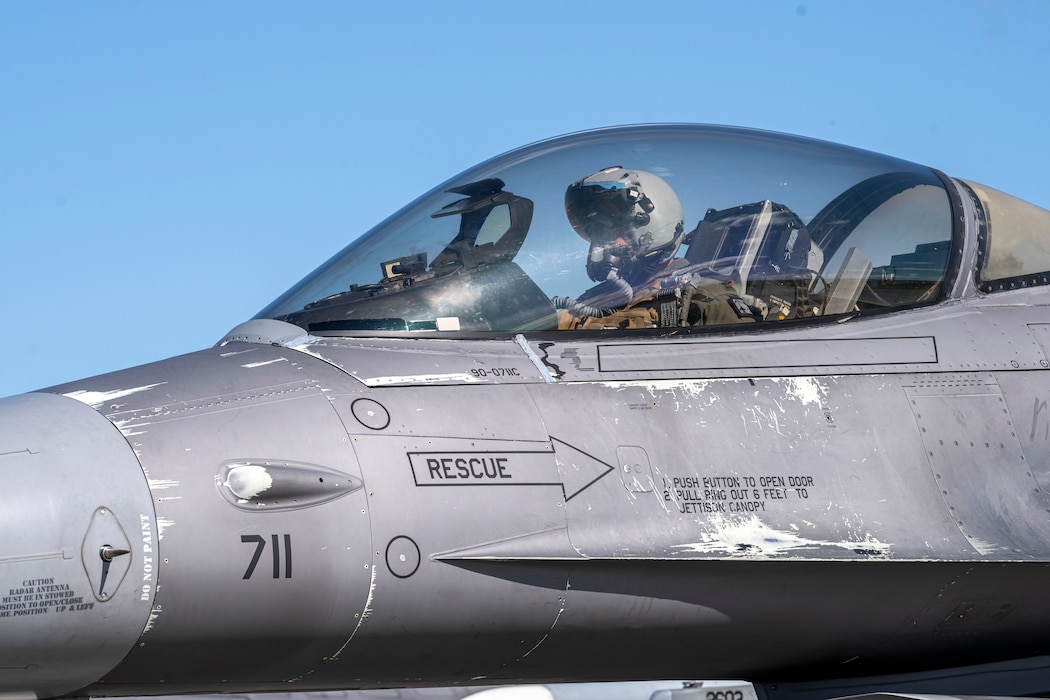 A pilot sits in a jet looking at his controls.