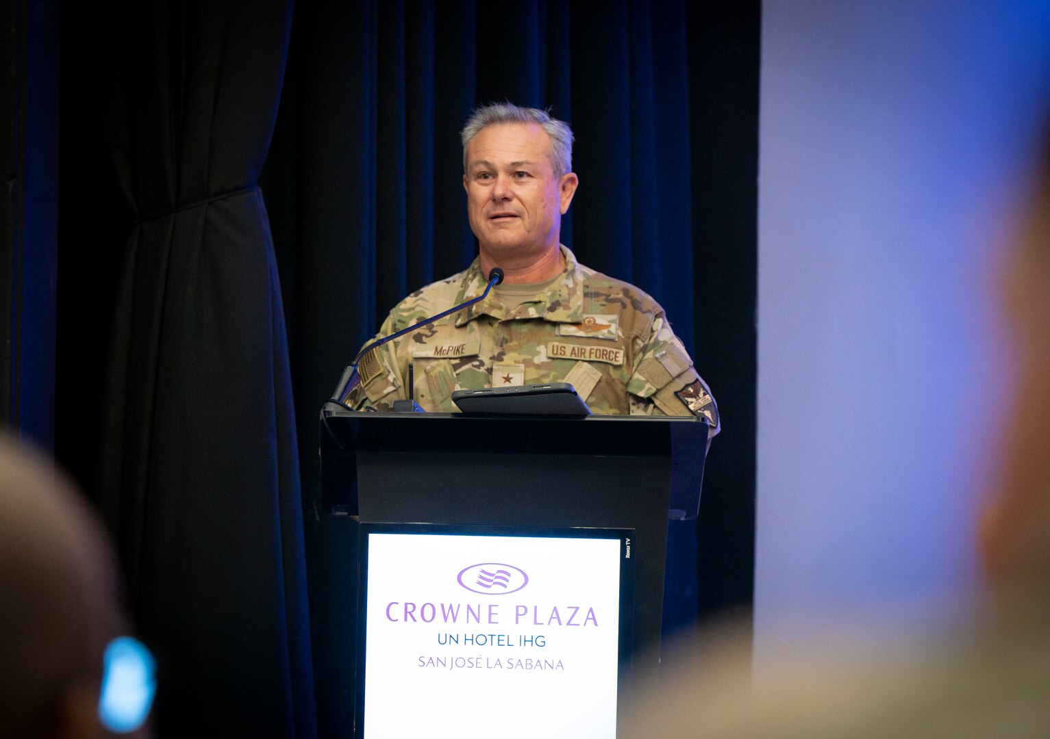 a photo of a man speaking at a podium.