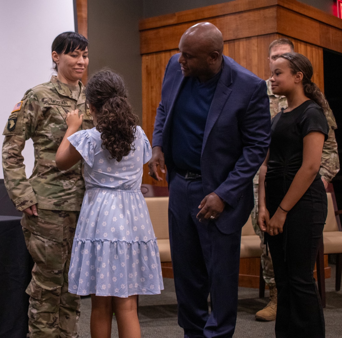 Guided by their father, Maj. Anthony McClain, Amelia and Olivia McClain, daughters of newly promoted Maj. Tarah McClain, Executive Officer, Recruiting and Retention Battalion, Illinois Army National Guard, secure the new rank during a promotion ceremony May 31 at the Illinois Military Academy, Camp Lincoln, Springfield.